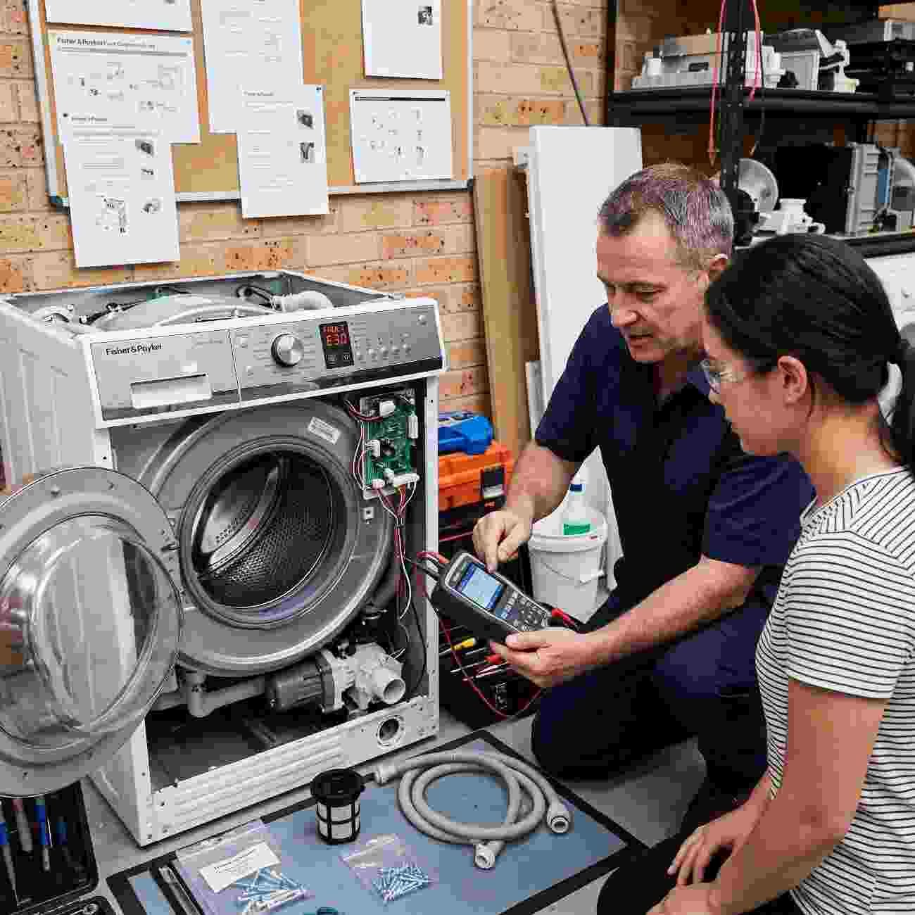 Sydney Appliance Services technicians diagnosing a Fisher & Paykel washing machine fault with a diagnostic tool