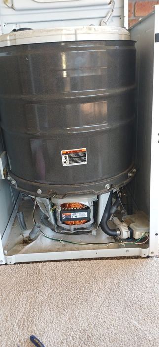 Washing machine drum removed from cabinet for repair