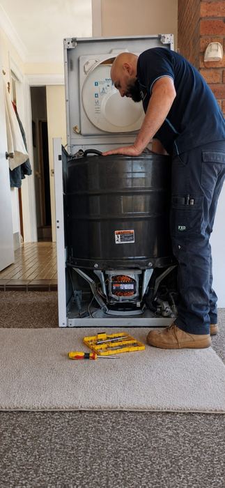 Technician servicing a stacked washer-dryer unit